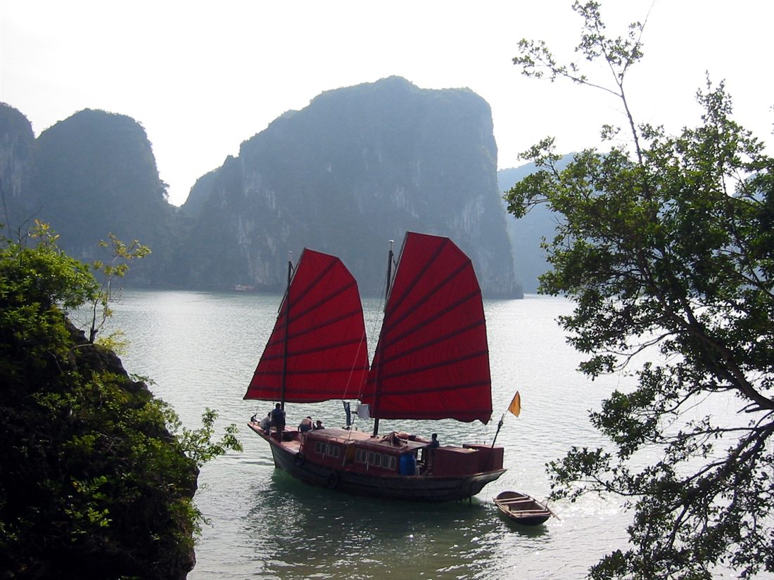 Red-sailed junk boat among the karsts of Ha Long Bay